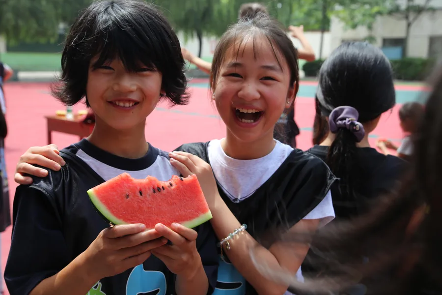 洛阳公益助学活动中，两位孩子拿着西瓜开心地笑着